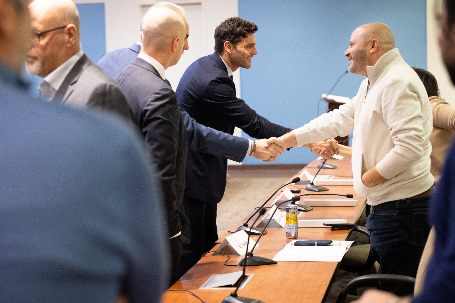 Max Rayetsky greeting Eli Weiss with a handshake at the dais after the panel