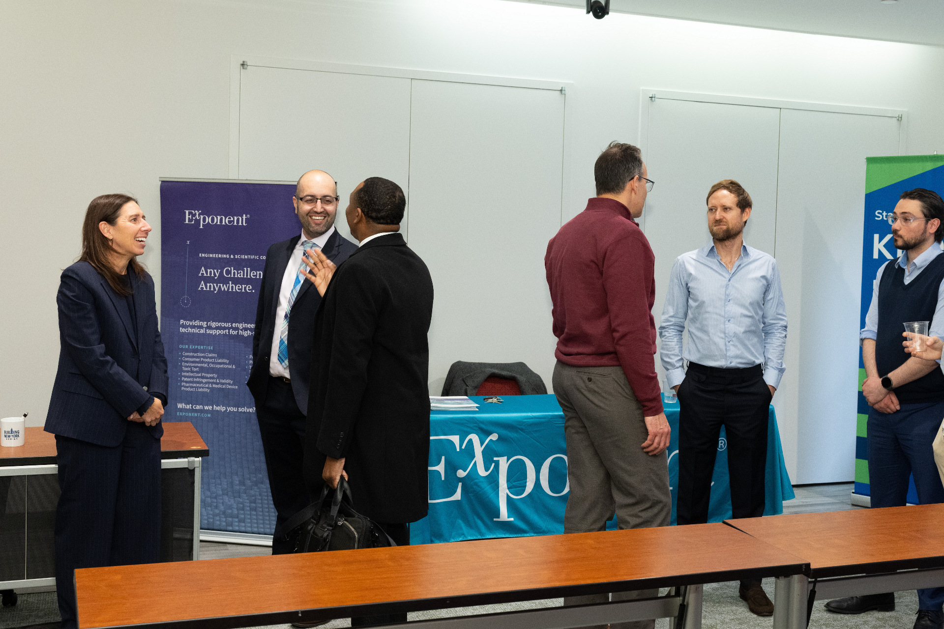Attendees networking with sponsors at the Exponent table during the airport development event reception