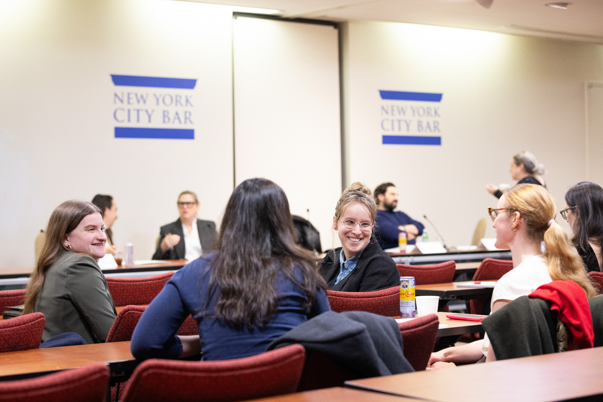 Attendees laughing together at a table in front of the New York City Bar signage