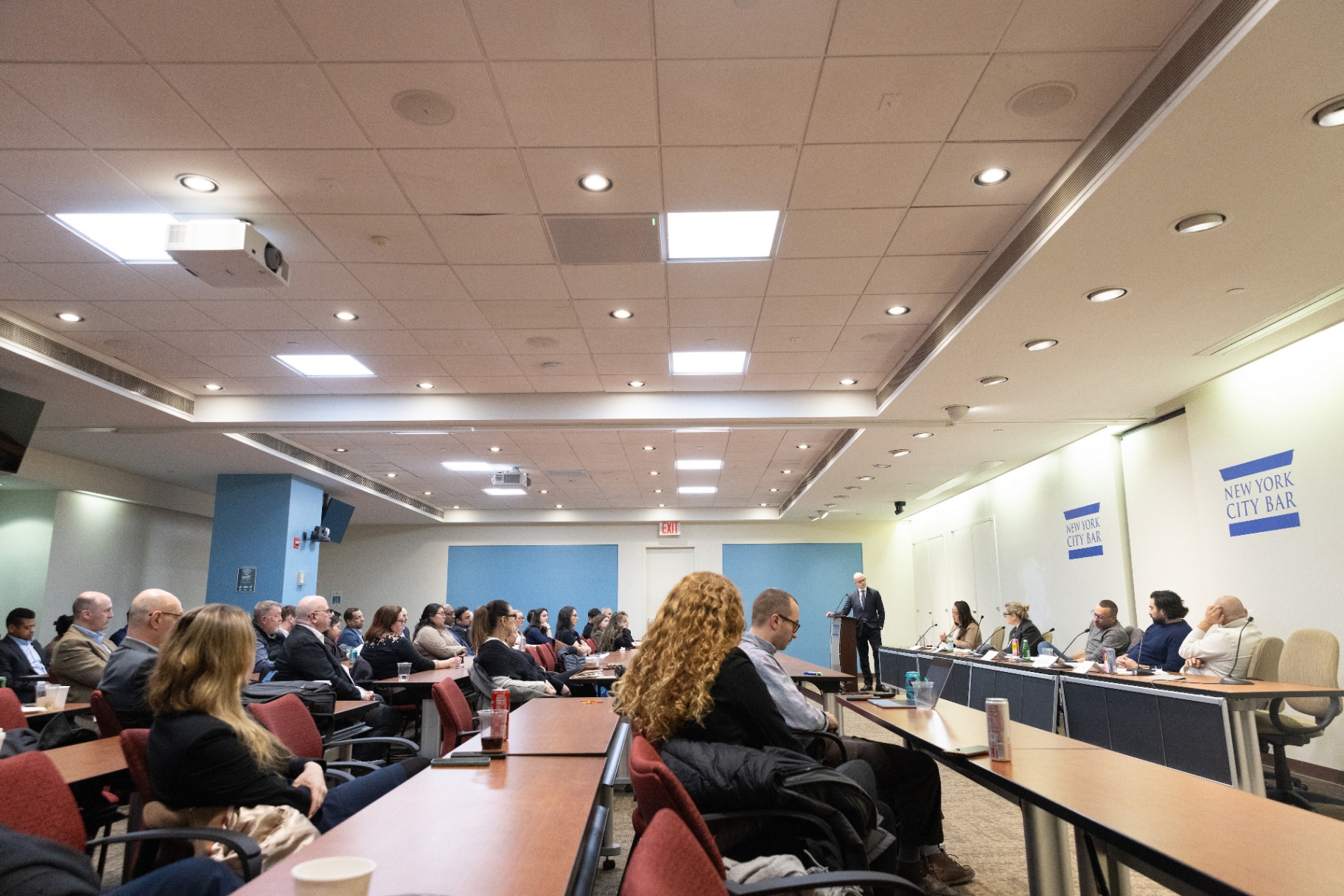 Wide view of the audience and dais with Max Rayetsky at the podium during the panel