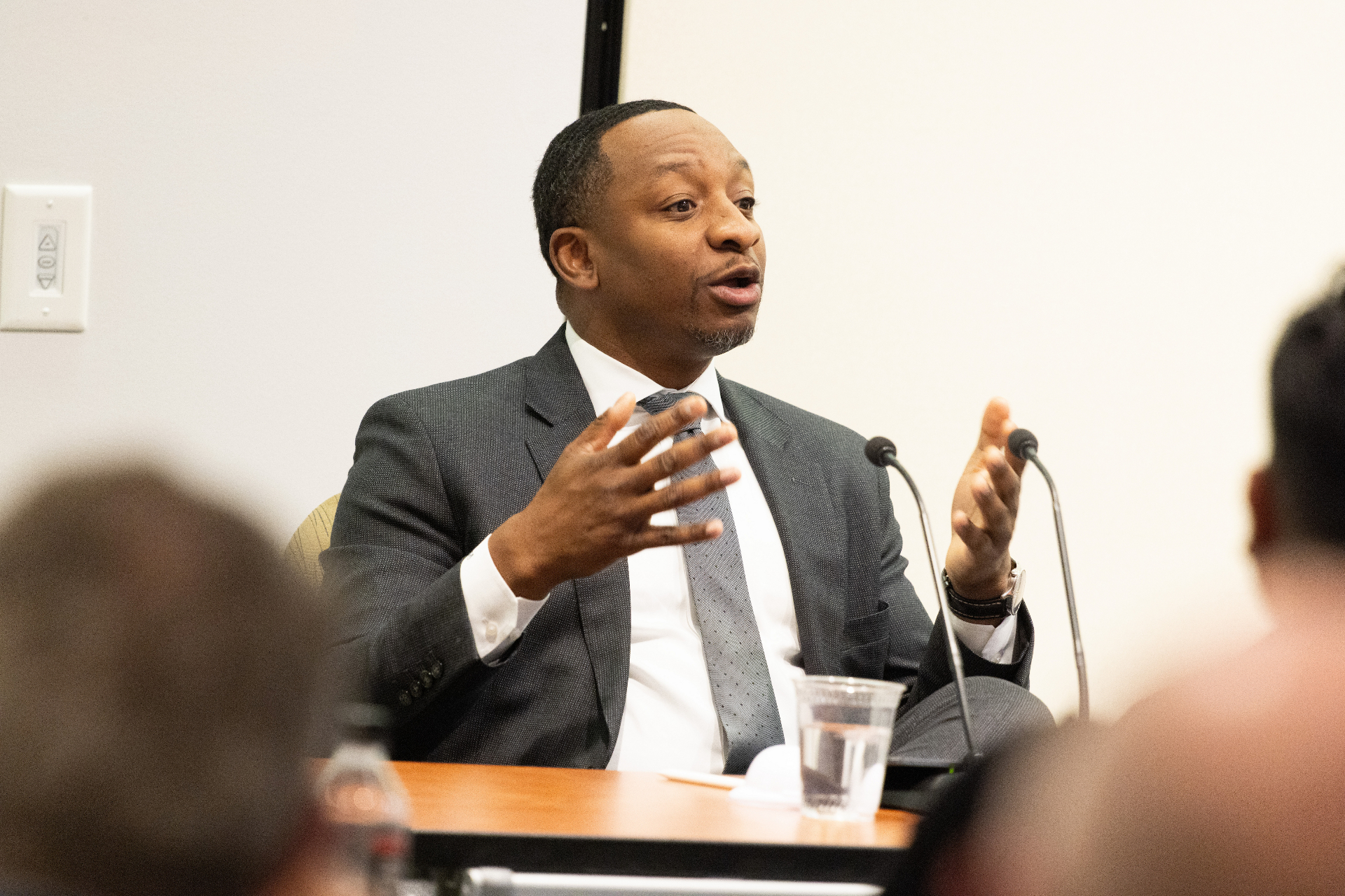 Panelist gesturing with both hands while speaking into the microphone during the airport development discussion