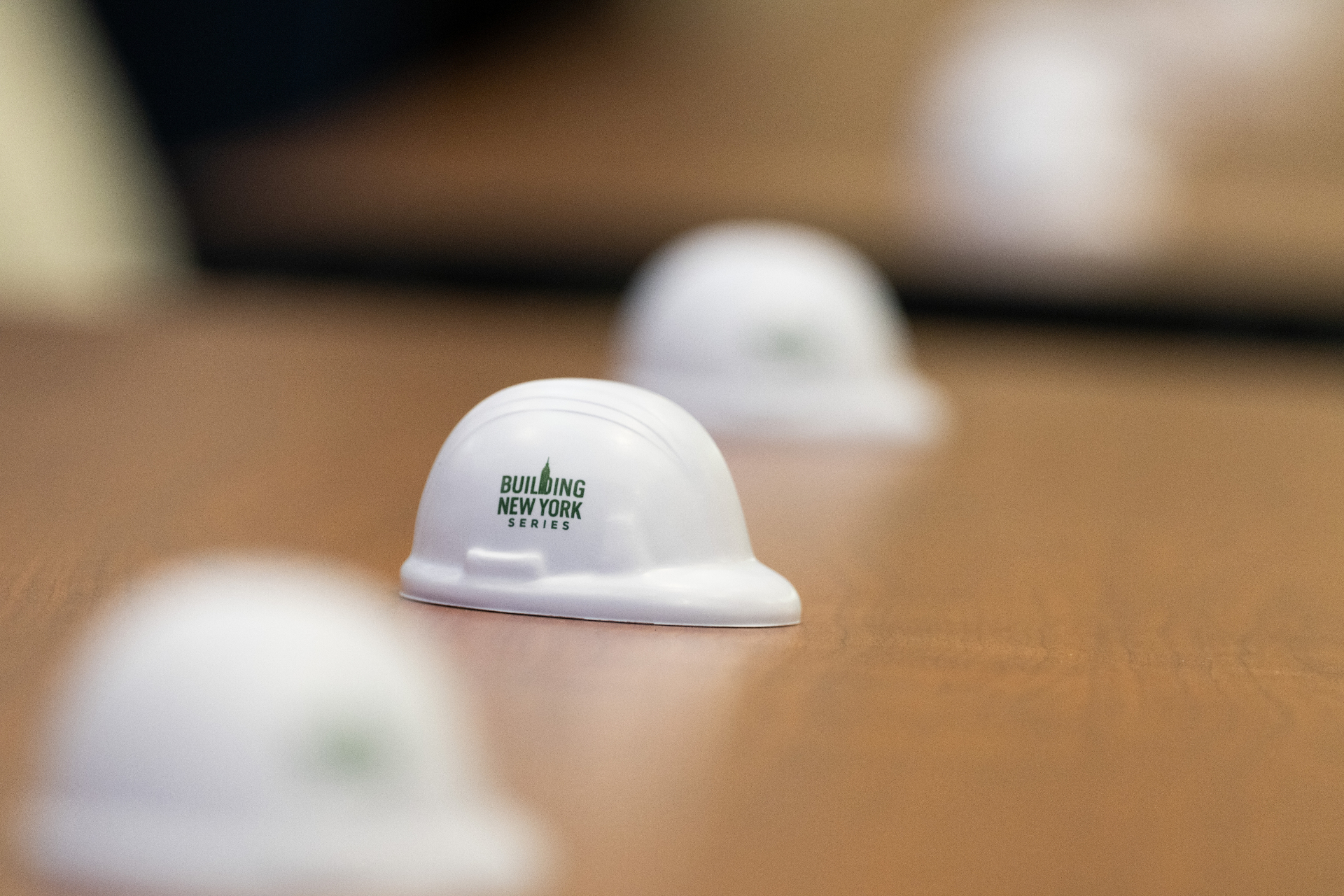 Building New York Series branded mini hard hats placed along the panel table